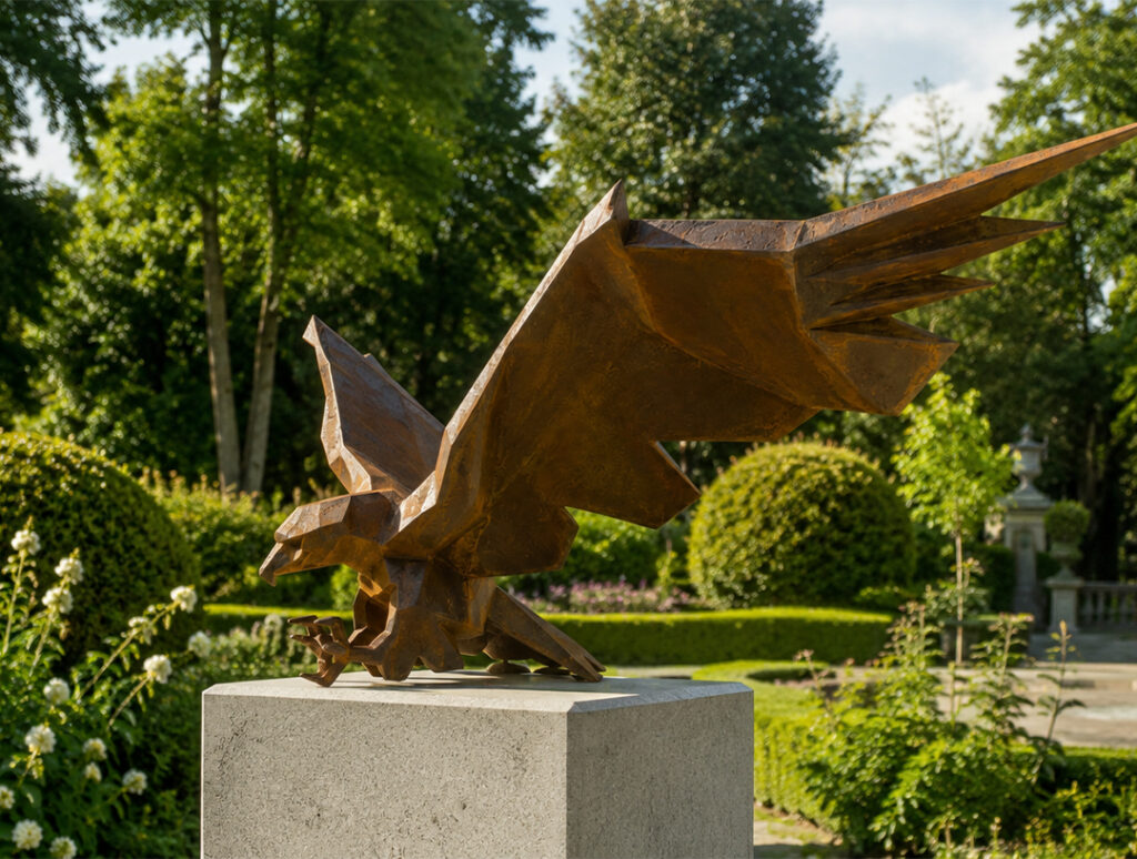 Sculpture géométrique d’un aigle en acier Corten aux ailes déployées, installée sur un socle dans un jardin