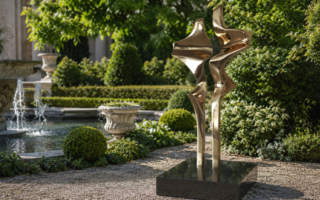 Sculpture abstraite en laiton poli composée de deux formes verticales dans un jardin paysager avec fontaine