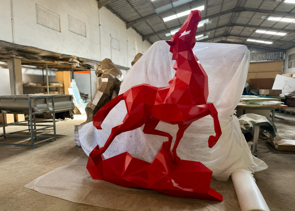 Sculpture géométrique rouge représentant un cheval cabré dans un atelier de sculpture au Maroc